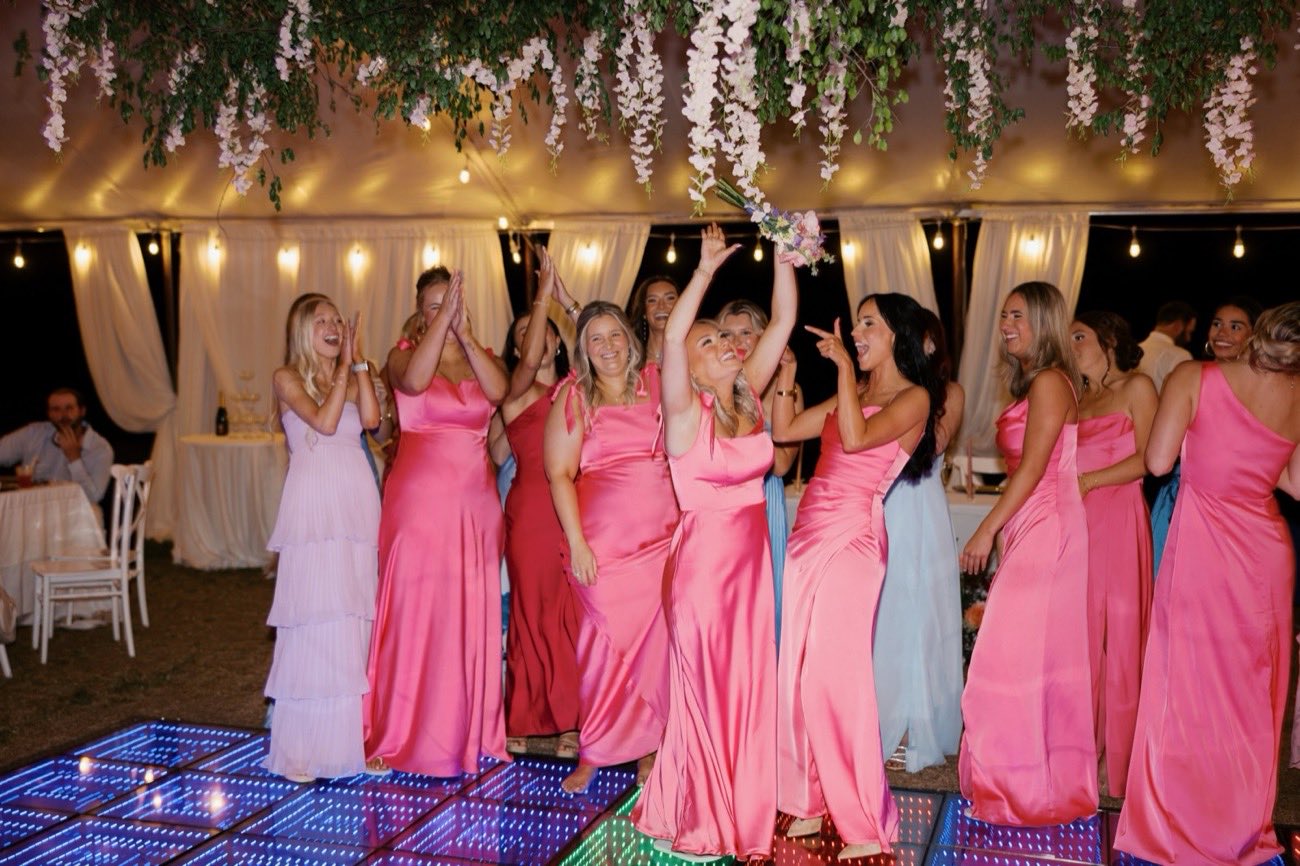 Bridesmaids cheering as the bridal bouquet is tossed on the LED dance floor