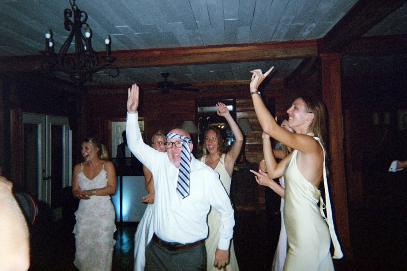 Guest dancing with a tie tied around his head, arms raised