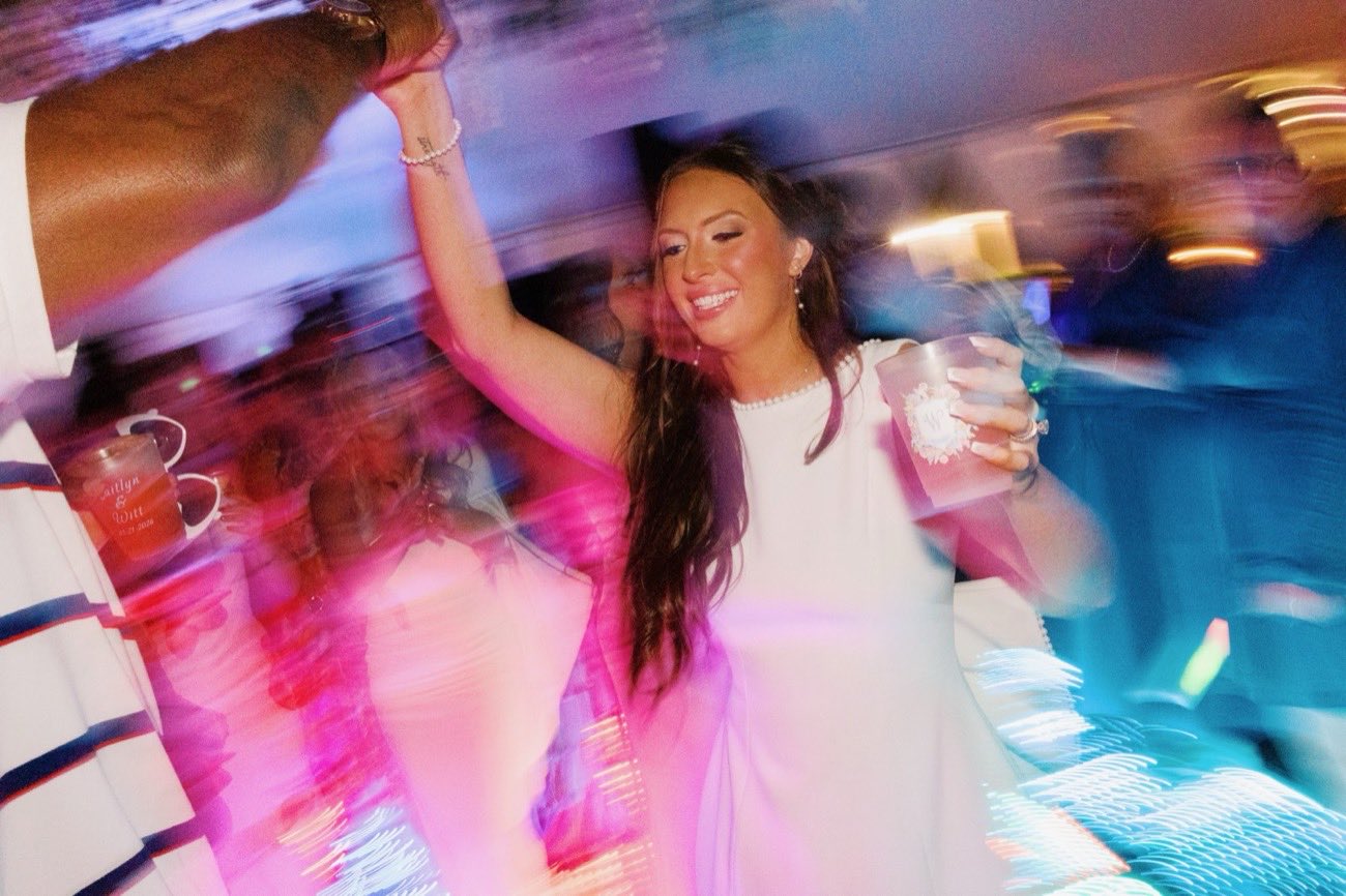 Bride dancing joyfully with a personalized wedding cup in hand
