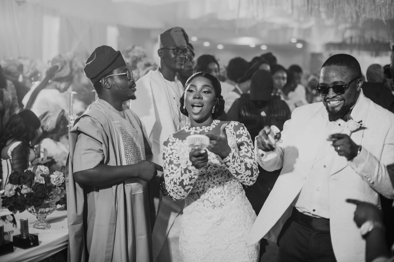 Bride and groom celebrating with guests in traditional attire at a Nigerian wedding reception
